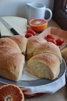 some bread is on a plate with oranges and other food items around the table