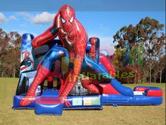 an inflatable spiderman bouncer is on display at the park with other inflatable toys