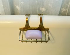 an old fashioned bathtub with two soap bars attached to the side and a curtain behind it