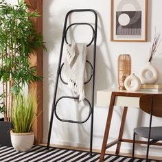 a towel rack in the corner of a room with a potted plant and pictures on the wall