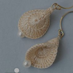 a pair of earrings with pearls hanging from it's hooks on a gray surface