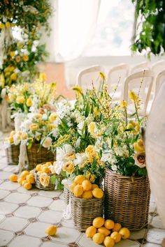 yellow and white flowers in wicker baskets lined up on the floor next to chairs