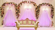 a white couch sitting in front of a pink wall with flowers on it's walls