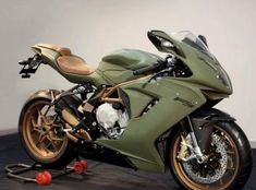 a green motorcycle parked on top of a wooden floor