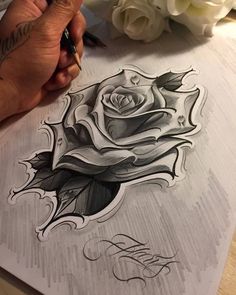 someone is drawing a rose with pencils on paper