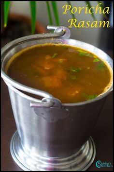 a metal bucket filled with soup on top of a wooden table