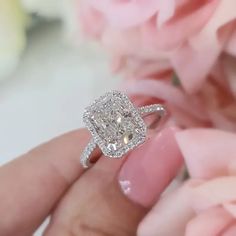 a close up of a person's hand holding a diamond ring