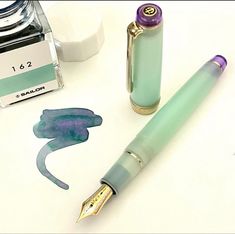 a fountain pen sitting next to a bottle of ink