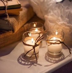 three candles are sitting on a table next to some books and a bag with twine