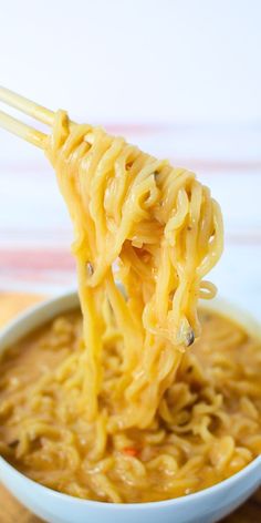 noodles being lifted from a bowl with chopsticks