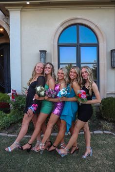 four beautiful young women standing next to each other in front of a building with large windows