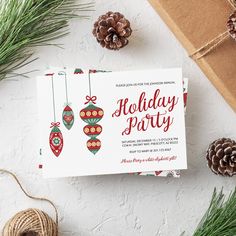 a holiday party card sitting on top of a table next to pine cones and twine