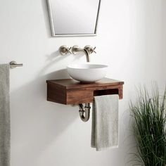 a bathroom sink sitting under a mirror next to a towel rack and potted plant