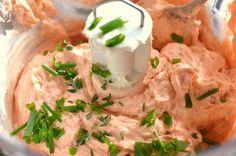 a food processor filled with mashed carrots and sour cream cheese, topped with green chives