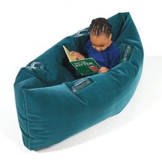 a young child sitting in a bean bag chair reading a book