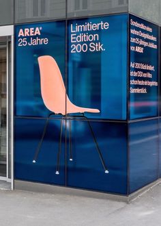 a blue box with an orange chair on it's side in front of a building