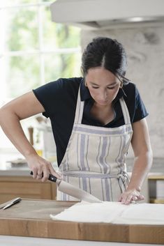 a woman in an apron is cutting something with a knife