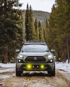 the front end of a gray toyota rav driving down a snow covered forest road