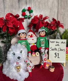 there are three christmas elves sitting next to each other on a table with a sign that says, take your santa claus $ 1