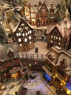 an aerial view of a christmas village with lights and snow on the ground, including buildings