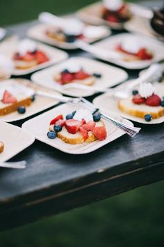 small desserts are arranged on white plates with blueberries and strawberries in them