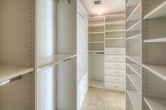 an empty walk - in closet with white shelving and shelves on both sides,