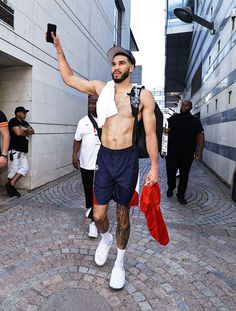 a shirtless man walking down the street with his cell phone