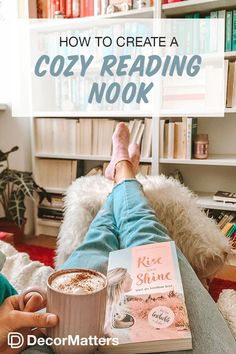 a person sitting on a couch reading a book and holding a cup of hot chocolate