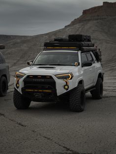 two vehicles parked in the desert on a cloudy day