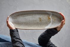 a person holding a white plate with brown speckles