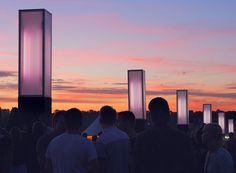 a group of people standing next to each other in front of a sky filled with clouds