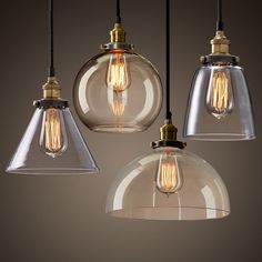 three clear glass pendant lights hanging from a ceiling fixture with one light bulb turned on