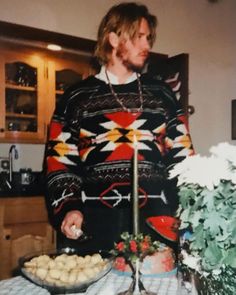 a man standing in front of a table with food on it and flowers behind him