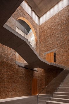 an empty room with stairs leading up to the second floor and a brick wall behind it