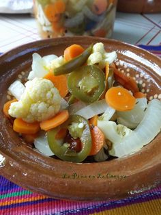 a brown bowl filled with vegetables on top of a table