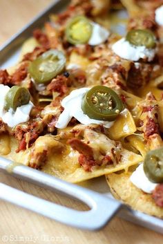 a plate full of nachos topped with cheese and jalapenos