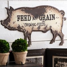 two potted plants sit next to a metal sign that says feed me grain organic feeds