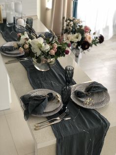 the table is set with plates, silverware and flowers in vases on it