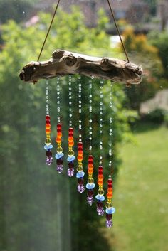 a wind chime hanging from a tree branch with beads and chains attached to it