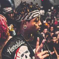 a woman with dreadlocks standing in front of a crowd holding her hand up