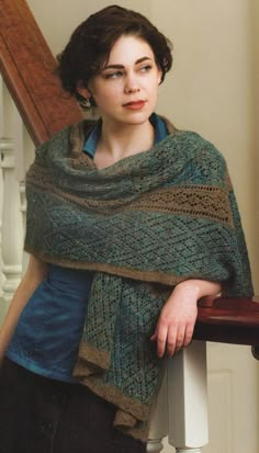 a woman wearing a shawl leaning on a stair rail with her hand on the railing