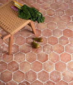 a wooden bench sitting on top of a tiled floor next to green leafy vegetables