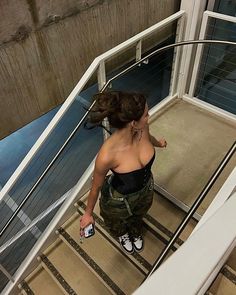 a woman is walking up the stairs with her hand on her hip and looking down