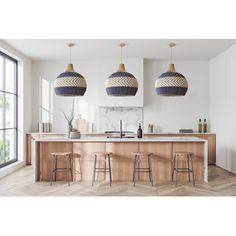 three pendant lights hanging from the ceiling above a kitchen island with stools and countertop