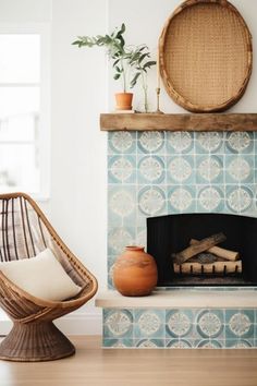 a living room with a fireplace, wicker chair and potted plant