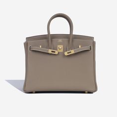 The Hermès Birkin is among the most famous bags in the world. First created in 1983 after Jean-Louis Dumas met Jane Birkin on a flight from Paris to London. In the short flight, Birkin explained that she needed a bag which was spacious enough for everything she needed to carry, with plenty of pockets as well. He sketched the first bag there and then, and the rest is history. More than thirty years later, this bag has been created in a huge variety of styles and materials. SPL Exterior Etoupe Togo Leather Gold-tone hardware Hermès logo stamp Two rolled leather handles Twist lock close Protective feet U code - 2022 Production Brand New condition Interior Matching interior Single compartment Zip pocket Slip pocket Brand new condition Sold with box, dust bag and lock & keys SPL Height 19cm Wid Birkin Bag Design, Hermes Birkin Etoupe, Paris To London, Hermes Birkin Bag, Classy Purses, Dream Bags, Hermes Birkin 25, Togo Leather, Bags Luxury