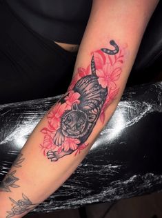 a woman's arm with a cat and flowers on it