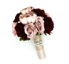 a bridal bouquet with red and pink flowers on it's side, in front of a white background