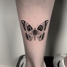 a woman's leg with a skull and butterfly tattoo on the side of her leg