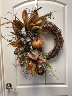 a wreath is hanging on the front door with autumn foliages and pineconis